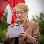 Kobieta czyta tekst z kartki i mówi do mikrofonu.