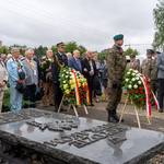 Uczestnicy uroczystości stoją, przed nimi stoi kilku mundurowych oraz wieńce.