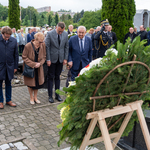 Zastępca prezydenta Rafał rudnicki oraz kilka osób pochyla głowę przed pomnikiem, na pierwszym planie fragment wieńca.