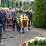 Zastępca prezydenta Rafał Rudnicki oraz kilku innych uczestników idzie za funkcjonariuszem w mundurze który niesie wieniec.