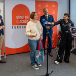 Lena Zadarozhnaya mówi do mikrofonu podczas konferencji prasowej, obok stoi dziennikarka oraz dwie osoby w tle.