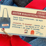 Metka przy torbie z tekstem „Cześć! Jestem białostocką torbą; Uszyły mnie wolontariuszki, bym mogła łączyć ludzi! „Białystok. Tu mieszkam” - oznacza, że to nasze miasto - bez względu na to, skąd pochodzimy i jak długo tu jesteśmy.”