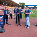 Marcin Rosengarten mówi do mikrofonów podczas konferencji prasowej, obok stoją dziennikarze.
