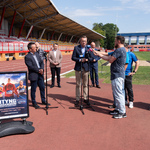 Zastępca prezydenta Rafał Rudnicki mówi do mikrofonu podczas konferencji dotyczącej Mityngu Gwiazd na Stadionie Lekkoatletycznym, w tle stoi kilku innych uczestników