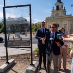 Dyrektor Muzeum Pamięci Sybiru Wojciech Śleszyński mówi do mikrofonu podczas konferencji prasowej, w tle Brama Wielka Pałacu Branickich.