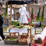 Stoisko z warzywami, obok stoi mężczyzna.