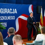 Mężczyzna mówi do mikrofonu przy mównicy podczas uroczystości.