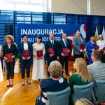 Kilka osób stoi trzymając bordowe teczki z dokumentem, obok stoi prezydent Tadeusz Truskolaski.