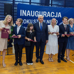 Grupa uczniów stoi z prezydentem Tadeuszem Truskolaskim, uczniowie trzymają w rękach teczki z dokumentami oraz medale.