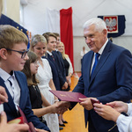 Prezydent Miasta Białegostoku wręcza uczennicy list gratulacyjny, obok stoją inni uczniowie.
