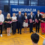 Uczniowie i nauczyciele stoją trzymając w rękach teczki, między nimi stoi prezydent Tadeusz Truskolaski.
