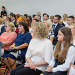 Goście uroczystości siedzą na krzesłach.