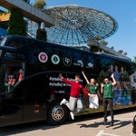 Troje studentów podskakuje radośnie obok zaparkowane po Operą i Filharmonią autobusu.