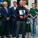 Marszałek Łukasz Prokorym stoi przed mikrofonami w czasie konferencji prasowej.