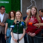 Studentka stoi przed mikrofonami w trakcie konferencji prasowej.