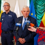 Prezydent Tadeusz Truskolaski mówi do mikrofonu, obok stoi funkcjonariusz policji.