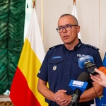 Funkcjonariusz policji mówi do mikrofonów.