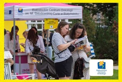 Dwie kobiety czytają ulotkę informacyjną, w rogu zdjęcia logo Białostockiego Centrum Onkologii.