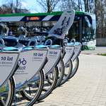 Rowery BiKeR stoją przy stacji, w tle jedzie autobus BKM.