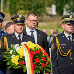 Zastępca prezydenta Tomasz Klim stoi w otoczeniu mundurowych podczas uroczystości.