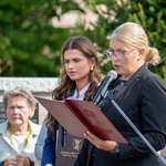 Prowadząca uroczystość mówi do mikrofonu, obok stoi inny uczestnik uroczystości.