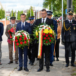 Zastępca prezydenta Tomasz Klim oraz wojewoda Jacek Brzozowski trzymają wieńce, za nimi stoją funkcjonariusze Straży Miejskiej oraz przedstawiciele innych instytucji.