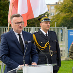 Zastępca prezydenta Rafał Rudnicki mówi do mikrofonu, obok stoi funkcjonariusz Straży Miejskiej.