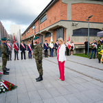 Kobieta i żołnierz stoją przed pomnikiem „Matki Sybiraczki w trakcie uroczystości, w tle stoją inni uczestnicy.