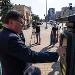 Zastępca prezydenta Marek Masalski kupuje bilet w nowym parkomacie, w tle stoi operator kamery oraz inni uczestnicy spotkania.