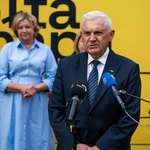 Prezydent Tadeusz Truskolaski mówi do mikrofonów podczas konferencji prasowej, w tle stoi kobieta.