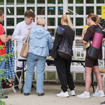 Kobiety i mężczyźni stoją przy stoisku oglądając wystawę.