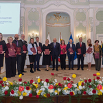 Grupa nauczycieli trzyma listy gratulacyjne, po środku stoi prezydent Tadeusz Truskolaski.