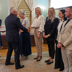 Prezydent Tadeusz Truskolaski podaje dłoń kobiecie podczas wręczania listów gratulacyjnych, obok stoją inni uczestnicy.