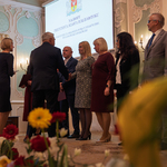 Prezydent Tadeusz Truskolaski wręcza listy gratulacyjne grupie osób stojących na podeście.