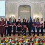 Grupa nauczycieli stoi w rzędzie pozując do wspólnego zdjęcia podczas uroczystości.
