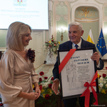 Prezydent Tadeusz Truskolaski trzyma dużą ramkę z grafiką, obok stoi kobieta.