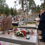 Zastępca prezydenta Rafał Rudnicki stoi przy grobie, na którym leżą złożone kwiaty oraz znicze 