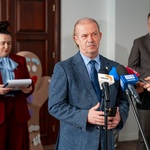 Mężczyzna mówi do mikrofonów podczas konferencji prasowej.