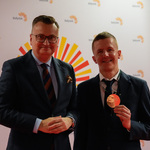Mężczyzna prezentuje otrzymany medal, towarzyszy mu zastępca prezydenta Rafał Rudnicki 