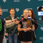 Młoda kobieta w okularach zabiera głos podczas spotkania
