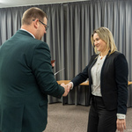 Zastępca prezydenta Tomasz Klim i kobieta podają sobie ręce w formalnej atmosferze. W tle znajduje się choinka ozdobiona świątecznymi dekoracjami.