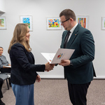 Zastępca prezydenta Tomasz Klim wręcza akt nauczycielce, w tle siedzą inni uczestnicy.