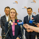 Kobieta stoi przed mikrofonami i udziela wywiadu podczas konferencji prasowej.