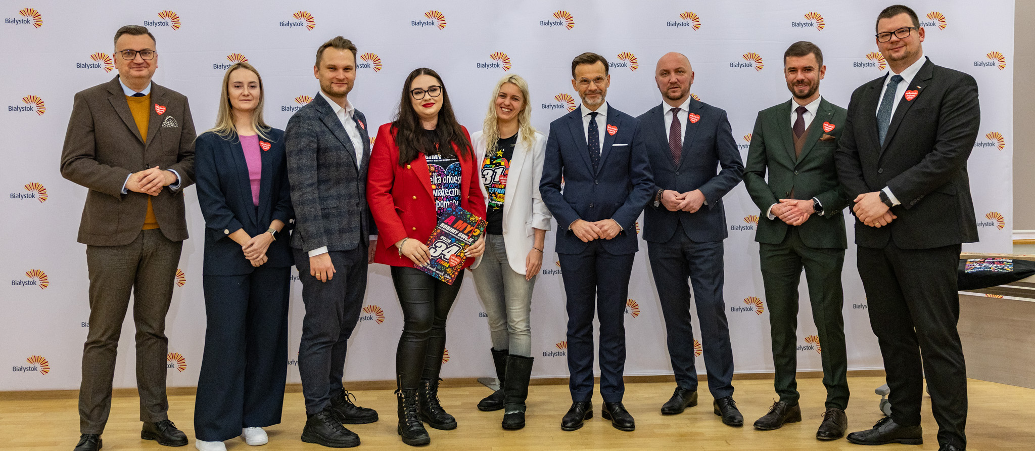 Dziewięciu uczestników konferencji prasowej stoi pozując do wspólnego zdjęcia.
