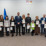 Zastępca prezydenta Tomasz Klim stoi razem z grupą osób nagrodzonych w konkursie pozując do wspólnego zdjęcia.