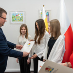 Zastępca prezydenta Tomasz Klim wręcza list gratulacyjny młodej kobiecie, obok stoją inne uczestniczki.