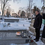 Zastępca prezydenta Rafał Rudnicki w asyście salutującego strażnika miejskiego stoi przy grobie oddając hołd zmarłym. Na grobie stoi zapalone światełko pamięci