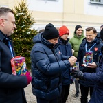 Uśmiechnięci wolontariusze podczas porannej kwesty. Prezydent Tadeusz Truskolaski wrzuca do puszki WOŚP pieniądze, obok stoi Wojewoda Podlaski Jacek Brzozowski oraz zastępca prezydenta Rafał Rudnicki 