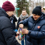 Prezydent Tadeusz Truskolaski wkłada pieniądze do puszki WOŚP. Na jego kurtce naklejone jest czerwone serduszko z napisem Wielka Orkiestra Świątecznej Pomocy