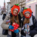 Dwie wolontariuszki przebrane za truskawki pozują do pamiątkowego zdjęcia. Jedna z dziewczyn trzyma w dłoni puszkę Wielkiej Orkiestry Świątecznej Pomocy, druga naklejki - czerwone serduszka z białym napisem Wielka Orkiestra Świątecznej Pomocy 